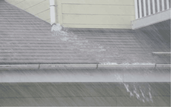 破損した雨漏りから水が噴き出る様子