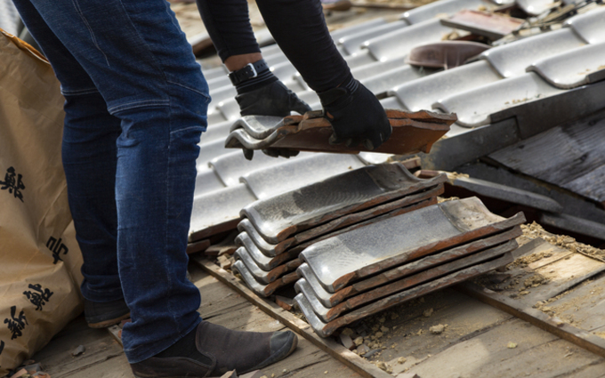 屋根材を持ち上げる職人